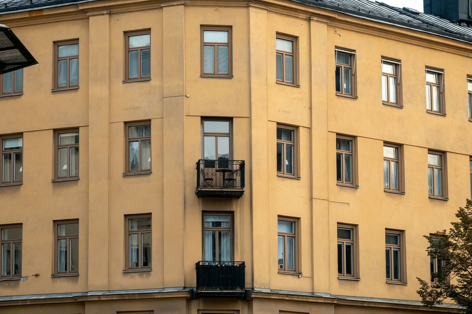 Gulmålad hyresfasad med balkonger i en svensk innerstadsmiljö